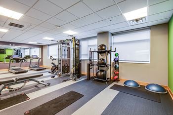 A gym with a variety of equipment including a treadmill, weights, and exercise balls.